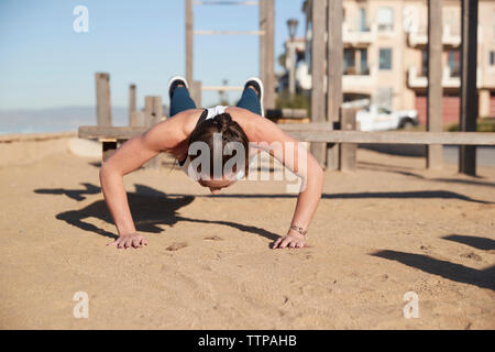 Woman doing push-ups at beach Stock Photo