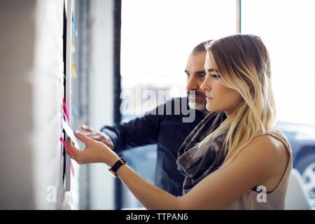 business people sticking adhesive notes on wall at creative office Stock Photo