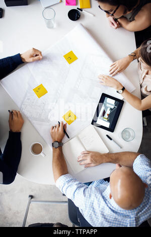 Overhead view of architects discussing over blueprints at creative office Stock Photo