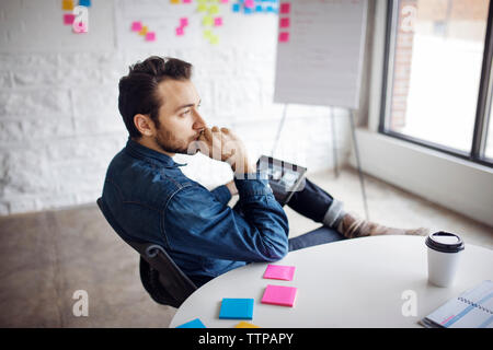 Thoughtful businessman using tablet while sitting at creative office Stock Photo