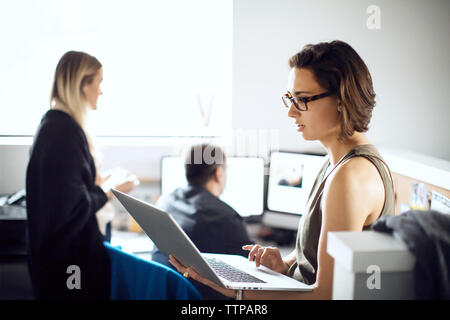 businesswoman using laptop while colleagues working in creative office Stock Photo