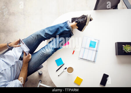 Low section of businessman using tablet sitting at creative office Stock Photo