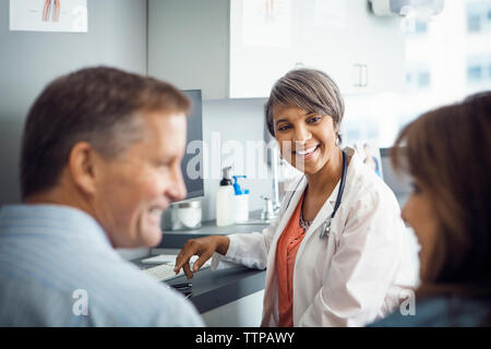 Happy female doctor looking at couple in clinic Stock Photo