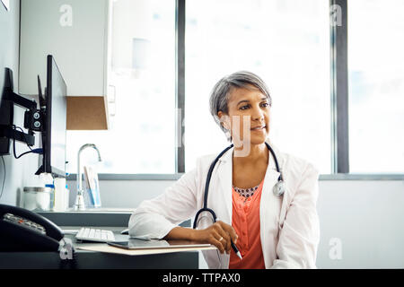 Confident female doctor sitting at desk in clinic