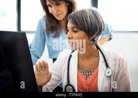 Female doctor explaining report on computer to patients in clinic Stock Photo