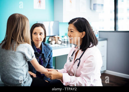 Smiling female doctor examining girl's hand in clinic Stock Photo