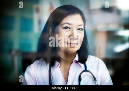 Portrait of confident female doctor seen through window Stock Photo