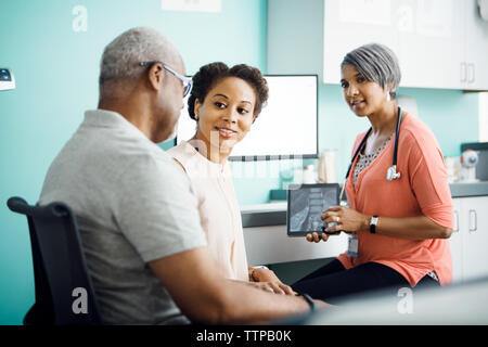 Daughter talking to father while sitting with female doctor in clinic Stock Photo