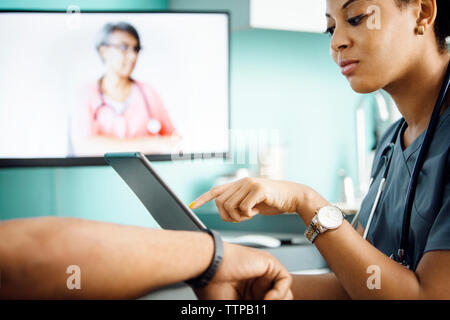 Female doctor using tablet computer with patient in clinic Stock Photo