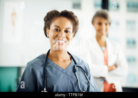Portrait of happy female doctor with colleague standing in background Stock Photo