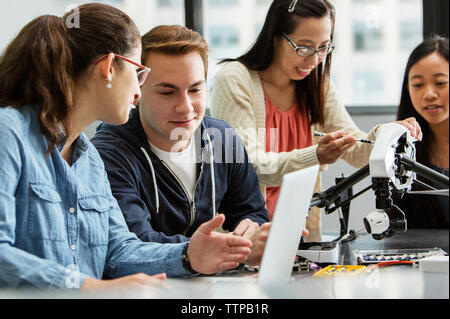 Teacher explaining drone while students discussing over laptop in classroom Stock Photo