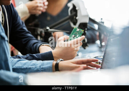 Cropped image of students holding circuit board in classroom Stock Photo