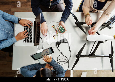 Overhead view of students working on electrical equipment at table in classroom Stock Photo