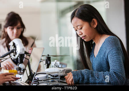 Concentrated female student using tablet computer while sitting with friends at table Stock Photo
