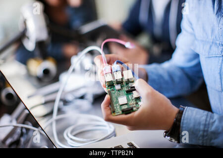 Cropped image of female student working on electrical equipment in classroom Stock Photo