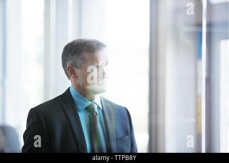 Thoughtful businessman standing in office Stock Photo