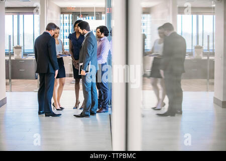 business people discussing while standing in office corridor Stock Photo
