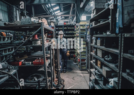 Portrait of female worker leaning on rack in factory Stock Photo