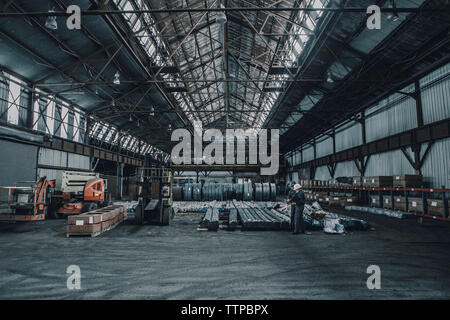 Mid distance view of coworkers discussing documents while walking in metal industry Stock Photo