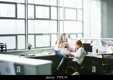 Female colleagues analyzing data at desk in office Stock Photo