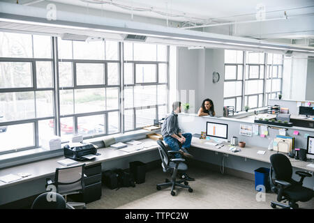 High angle view of business people talking while sitting at desks in office Stock Photo