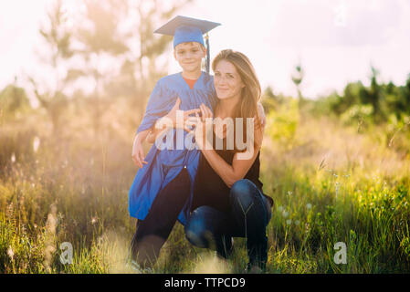 Portrait of mother with son wearing graduation gown Stock Photo