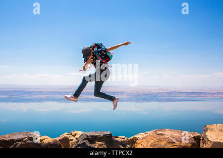 Happy woman jumping on mountain against sea Stock Photo