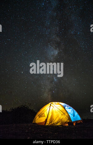 Illuminated tent on field against star field Stock Photo