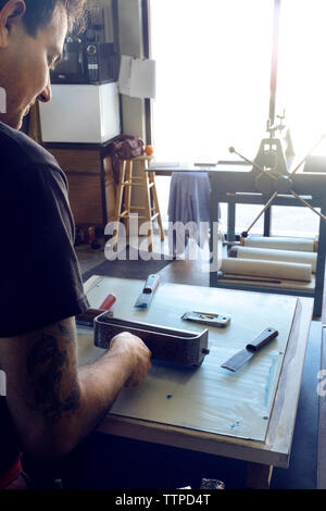 Cropped image of male lithograph worker using paint roller at workshop Stock Photo