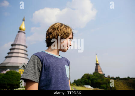 Boy looking away while standing against pagodas at Doi Inthanon National Park Stock Photo