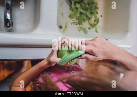 High angle view of girl peeling green apple at home Stock Photo