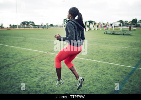 Full length of determined female athlete exercising on field Stock Photo