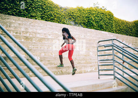 Rear view of sportswoman running on steps in stadium Stock Photo