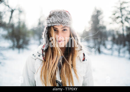 Portrait of smiling woman wearing fur hat at snow covered field Stock Photo