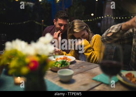 Happy couple sitting at table while enjoying dinner party with friends Stock Photo