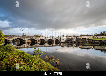 Arch bridge over river against cloudy sky in city Stock Photo