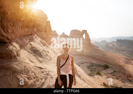 Portrait of woman visiting natural arch against clear sky Stock Photo