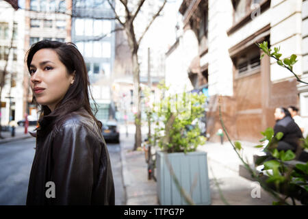 Side view of thoughtful young woman on city street Stock Photo