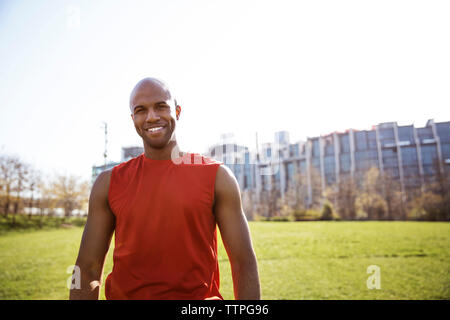 Portrait of smiling male athlete standing on grassy field in city Stock Photo