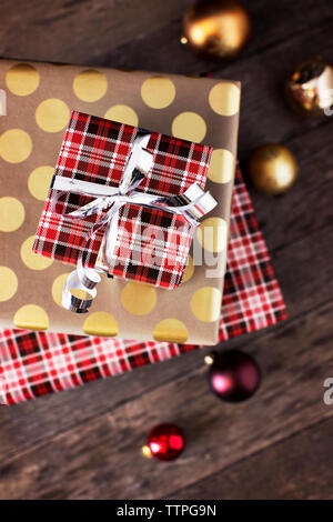 Overhead view of stack of christmas presents with baubles on wooden table Stock Photo