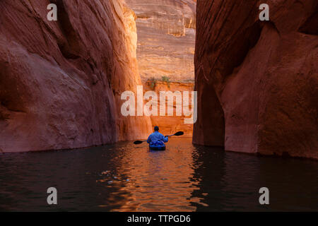 Rear view of hiker kayaking on Lake Powell amidst canyons Stock Photo