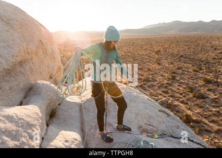 Hiker adjusting rope while standing on mountain during sunset Stock Photo