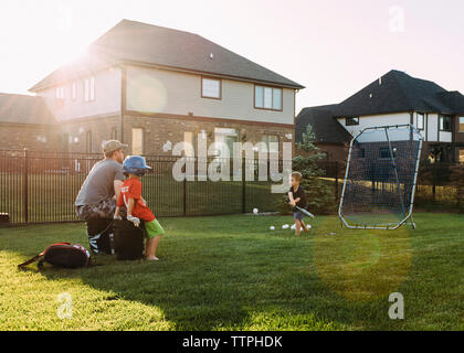 Family playing baseball at backyard on sunny day Stock Photo