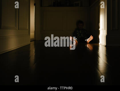 Boy sitting on floor in darkroom at home Stock Photo