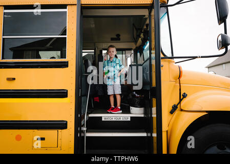 Portrait of boy with backpack standing in school bus Stock Photo