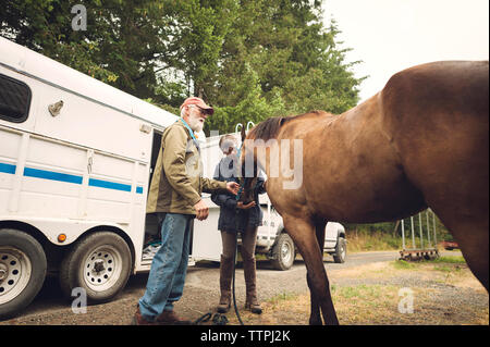 Female doctor examining horse while standing with man in farm Stock Photo