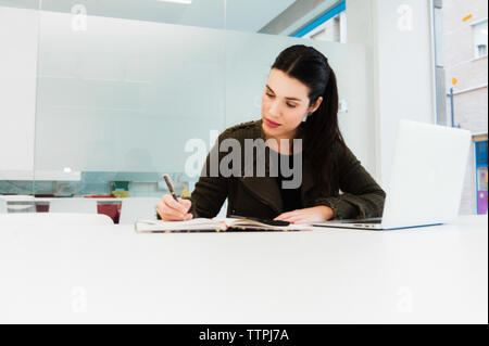 Young Hispanic Woman Working on Laptop in Classroom Stock Photo