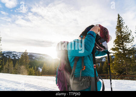 Woman wearing knit hat while standing on snowy field against sky Stock Photo