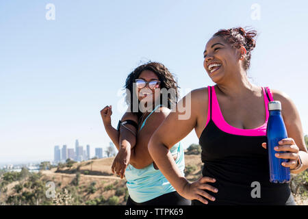 Happy female friends exercising against clear sky Stock Photo