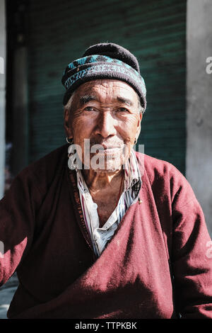 Portrait of senior man wearing warm clothing sitting in town Stock Photo